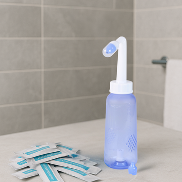 Comformidable neusdouche in badkamer op een wasbak met daarvoor zakjes spoezout