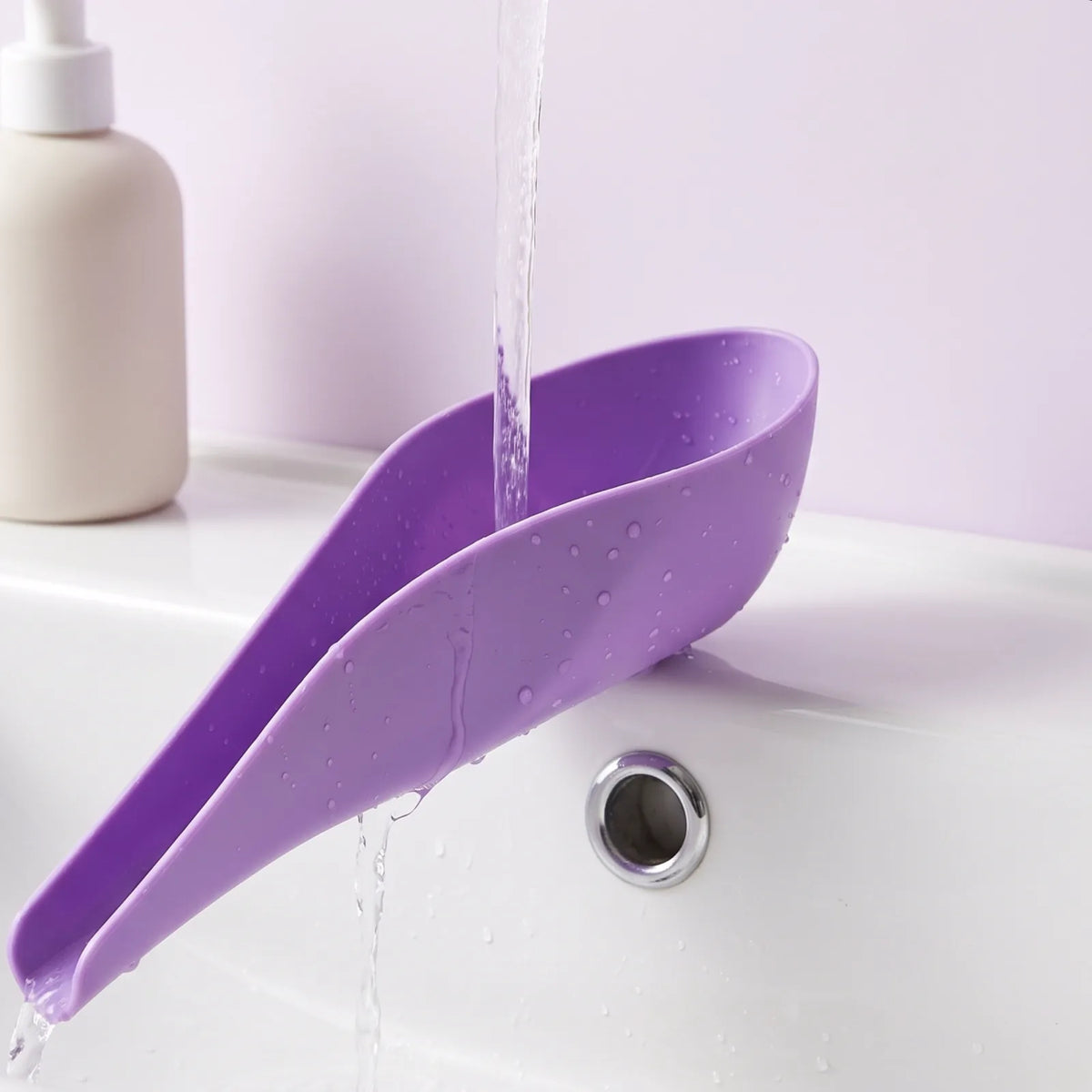 Lila Urinierhilfe wird unter dem Wasserhahn abgespült
