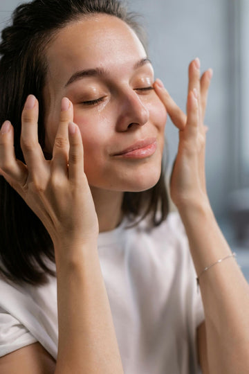 Vrouw die met haar handen huidverzorging aanbrengt op haar gezicht
